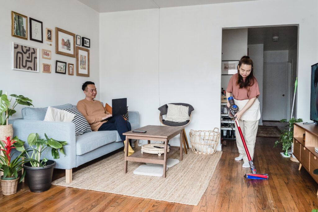 A woman cleaning the floor using a modern cordless Dyson vacuum cleaner.